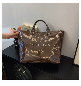 Detail of a dark brown glossy tote bag featuring unique crinkled patent leather texture