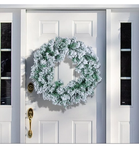 Close-up of artificial flocked Christmas wreath with snow effect on a white front door