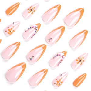 Faux ongles amande orange style français avec motifs marguerites et strass brillants