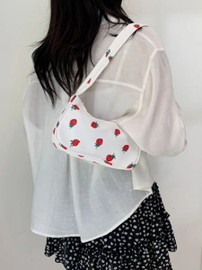 Back view of a model wearing a white nylon shoulder bag with red strawberry patterns