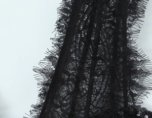 Détail du tissu en dentelle noire avec paillettes scintillantes sur une robe moulante