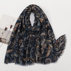 Detailed close-up of ethnic paisley pattern and fringe trim on a dark blue scarf
