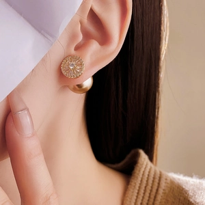 Close-up of gold-plated stud earring with sparkling zircon and pearl on a model's ear