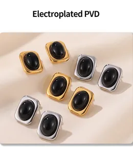 Close-up of gold and silver geometric stud earrings with black oval stones on silk