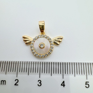 Detailed view of 18K gold angel wing pendant with white shell inlay and ruler for size