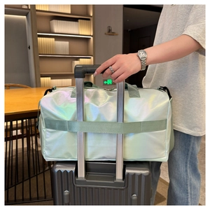 Green iridescent travel bag secured on suitcase handle for easy luggage transport