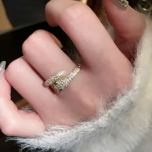 Gold plated snake ring with cubic zirconia and green gem eyes on a white soft background