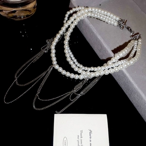 Détail d'un collier de perles multicouche avec chaînes à pompons argentées sur plateau noir