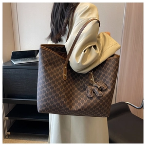 Detail of dark brown tote bag with M-pattern and cute animal charm for daily commuting
