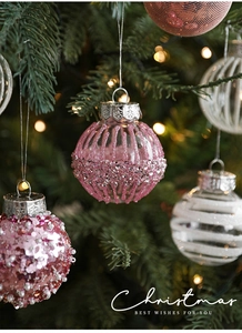 Close-up of pink glitter and sequin Christmas balls hanging on a decorated tree