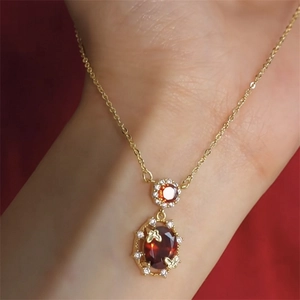 Macro view of a 18K gold plated necklace with red oval gemstone and butterfly accents