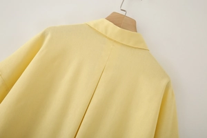 Macro detail of high-quality yellow linen shirt stitching on wooden hanger
