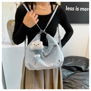Close-up of light blue shoulder bag with pleated texture and fluffy cloud pendant charm
