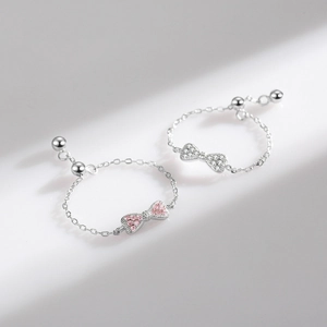 925 silver bow rings with pink and silver rhinestones on a clean surface