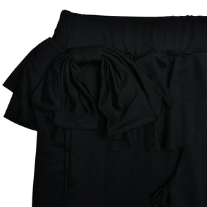 Dettaglio dei pantaloni a zampa neri con fiocco decorativo in tessuto e volant eleganti