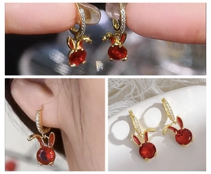 Detail of bunny drop earrings with red round stones and gold finish on the ears