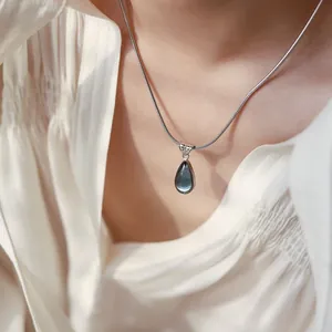 Detailed view of silver snake chain with a deep grey translucent teardrop stone pendant