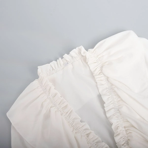 Detail of ruffled V-neckline on white chiffon dress with elastic smocked collar design