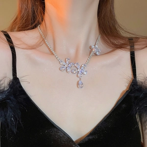 Close-up of a silver floral zircon necklace with a teardrop pendant on a model's neck