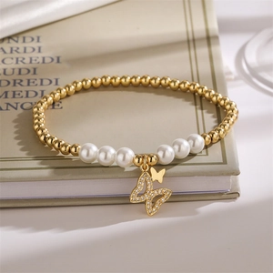 Close-up of pearl and gold bead bracelet with a crystal butterfly charm on a book