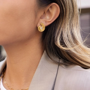 Boucles d'oreilles créoles spirales dorées avec zircons ronds sur un mannequin