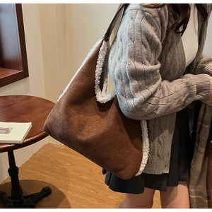 Brown suede tote bag with white faux shearling trim worn by model in a cafe setting