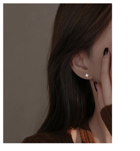 Macro detail of silver star stud earring with sparkling zircon on a female ear
