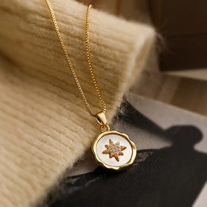 Vintage gold plated necklace with zircon bee star pendant on a soft woven background