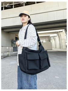 Black canvas messenger bag with large front flap pockets and adjustable strap for women