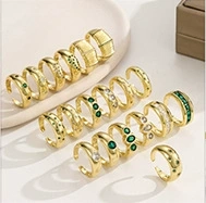 Detailed close-up of 14K gold plated rings set with green gemstones on a beige background