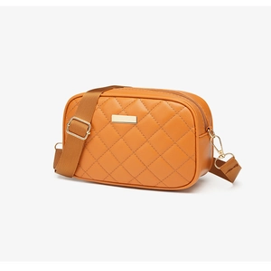 Close-up of orange quilted crossbody bag with golden zipper and adjustable shoulder strap