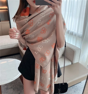 Detail of soft beige cashmere-like scarf featuring orange and white butterfly patterns