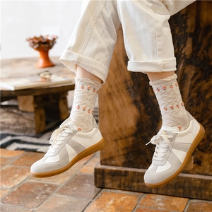 Detail shot of off-white knitted socks with small red strawberry patterns on feet