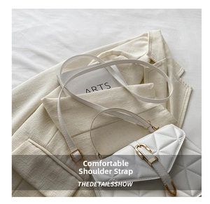 Close-up of white quilted crossbody bag with gold buckle hardware and fine leather texture