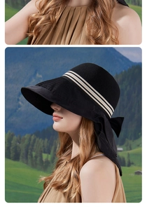 Detail of a black wide-brim sun hat with decorative striped ribbon and large bow design