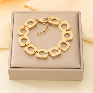 Détail du bracelet à maillons carrés plaqué or 18 carats mat sur un fond en tissu de soie