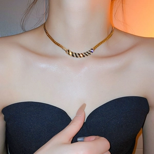 Detail of gold necklace with black and white striped pendant and sparkling crystals