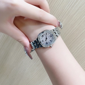 Detail of silver tonneau watch with Roman numerals and rhinestone bezel on a woman's wrist