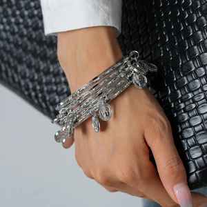 Detail of silver layered bangle set with portrait coin charms on a female model