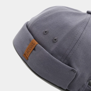 Close-up of grey docker hat showing high-quality twill fabric and leather logo patch