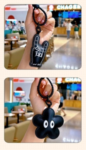 Detail showing two black PU leather keychains with rock gesture and flower designs