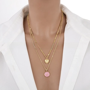 Close-up of a double-layer gold heart necklace with a pink enamel moon pendant
