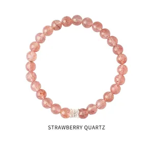 Detail of strawberry quartz beads with a silver bow charm on a minimalist white background