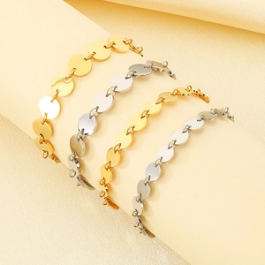Close-up of gold and silver polished metal disc bracelets on cream cylindrical props