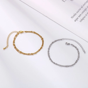Detail of minimalist double-layered stainless steel anklets with small metal beads