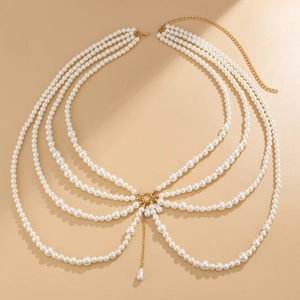 Detail of layered pearl body chain with golden ring and elegant teardrop pendant