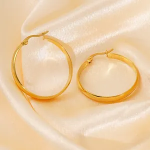 Classic large golden hoop earrings with smooth metallic finish on elegant silk background