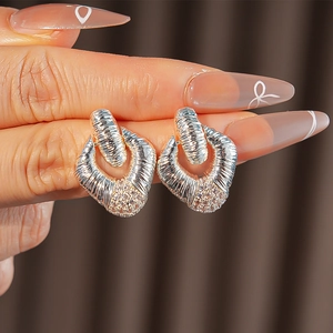 Close-up of silver and gold hoop earrings with sparkling cubic zirconia on finger