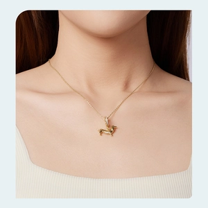Close-up of a golden dachshund pendant with zircon stones worn on a delicate chain