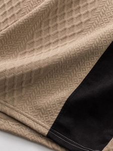Détail macro du t-shirt jacquard pour homme montrant la texture gaufrée beige et couture